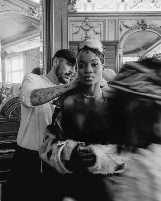 A stylist adjusting a model's collar backstage