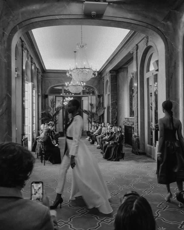Model walking the length of a mirrored salon corridor