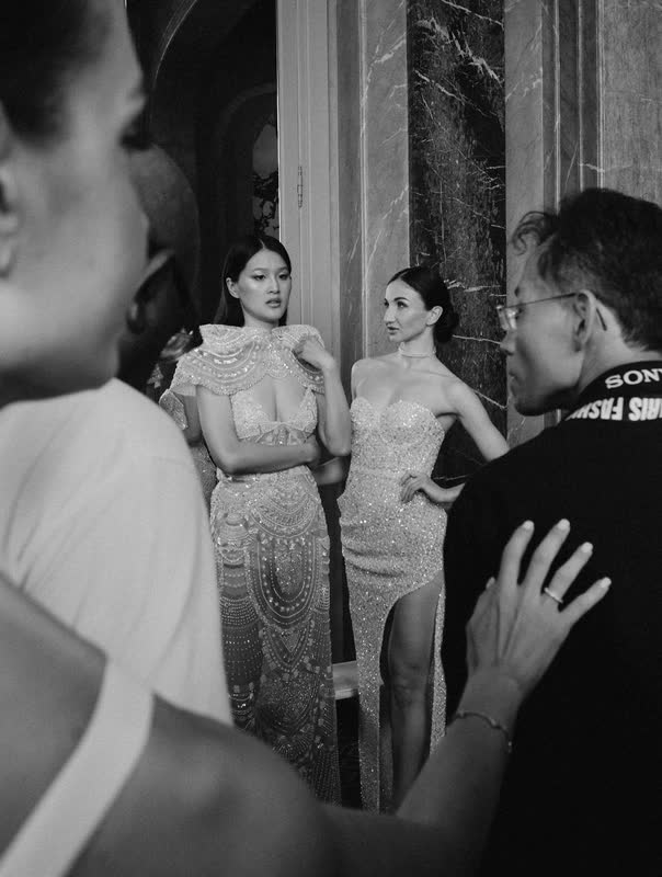 Models waiting in line as a dresser gestures beside them