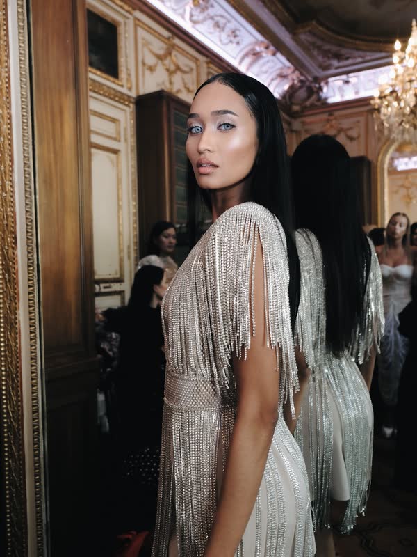 Model glancing back in a beaded, fringed gown