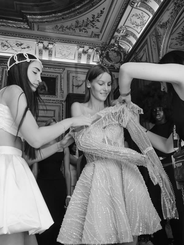 Dressers fitting a model into a white couture gown