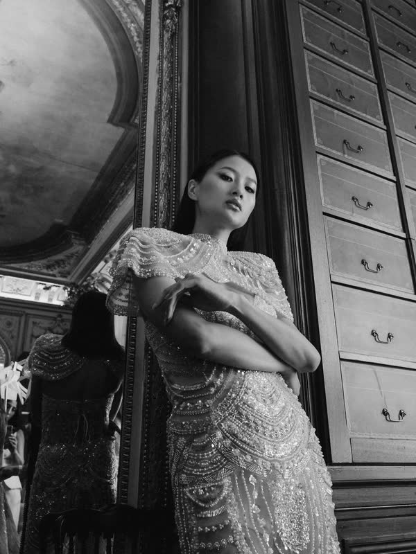 Model in a beaded dress leaning against an antique chest of drawers