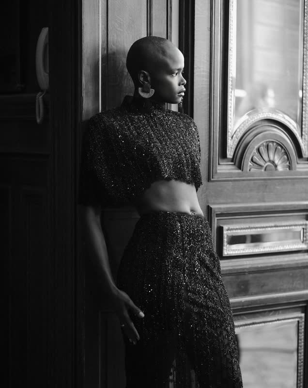 Model in a black textured ensemble framed in a doorway